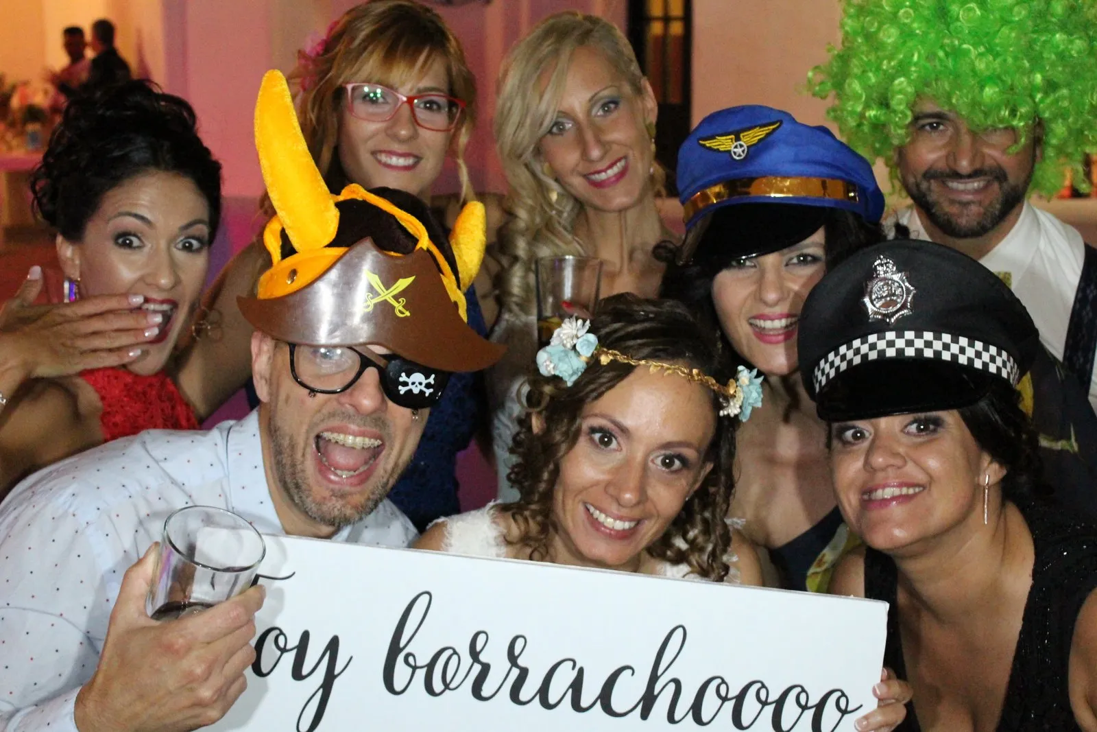 Invitados disfrazados con gorros y carteles divertidos