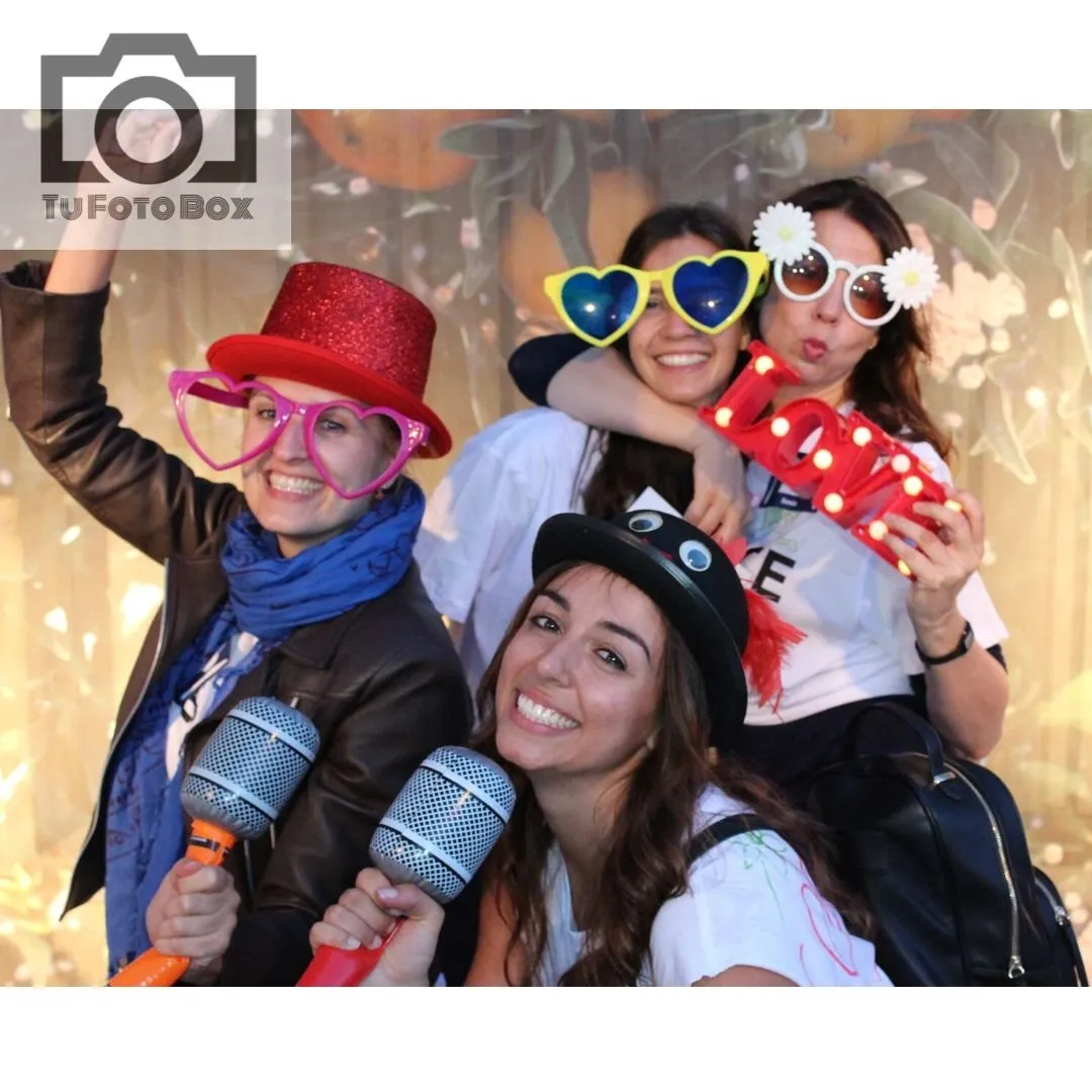 Amigas con sombreros, gafas y micrófonos de atrezzo